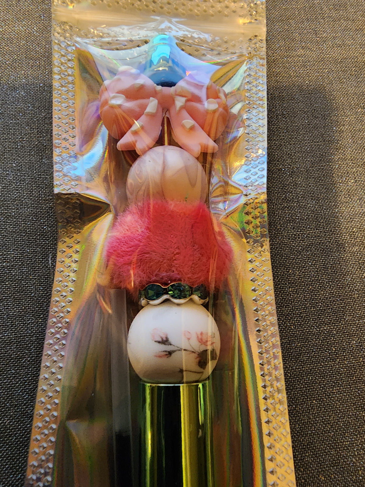 Pink bow with a pink fuzzy charm on a green pen