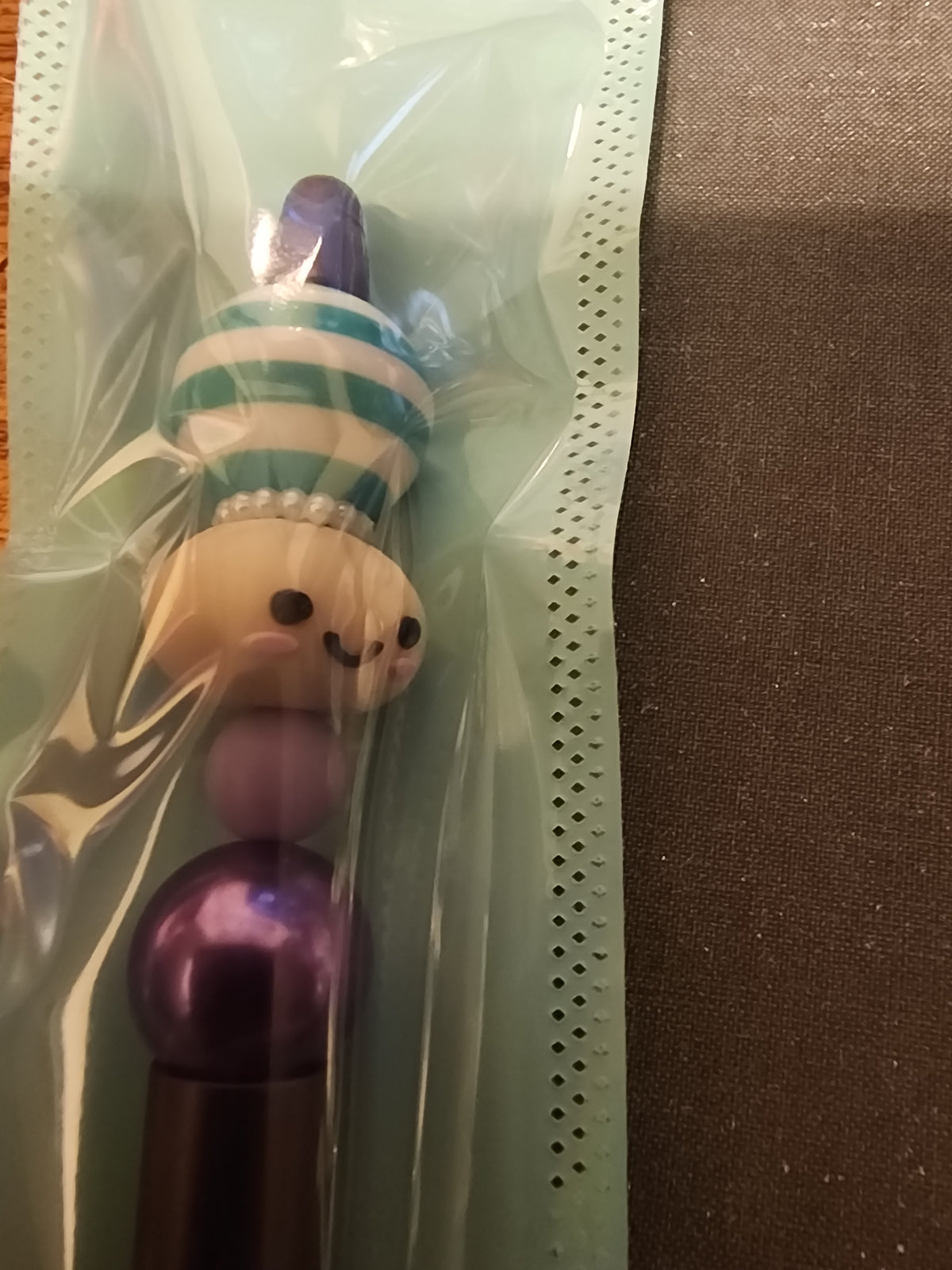Tan dumpling with bubblegum beads on a purple pen