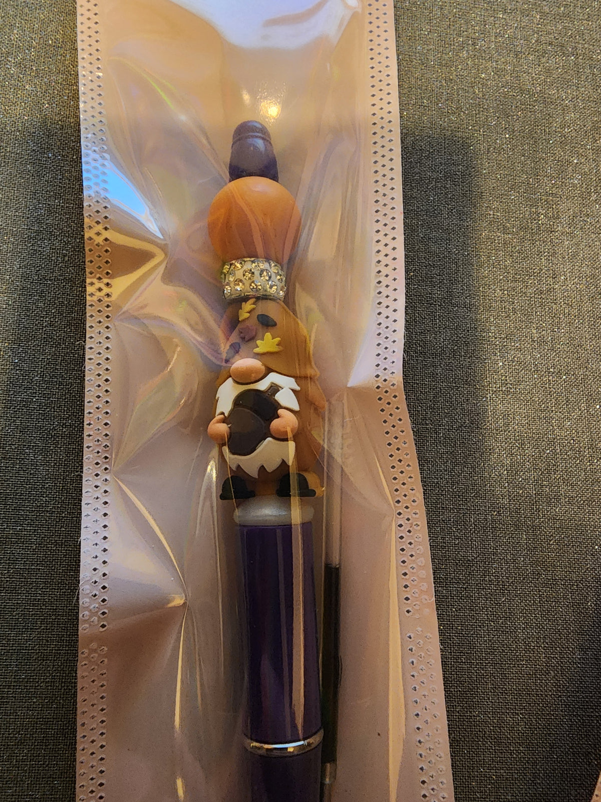 Tan gnome holding an acorn on a purple pen