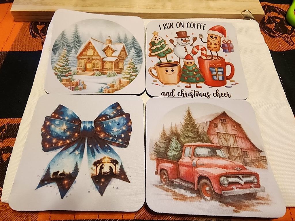 Four square coasters with rounded corners. The coasters feature festive holiday illustrations: a large blue bow with stars, a snowy cabin, a red vintage truck, and a coffee cup character with the text 'I RUN ON COFFEE AND CHRISTMAS CHEER'.